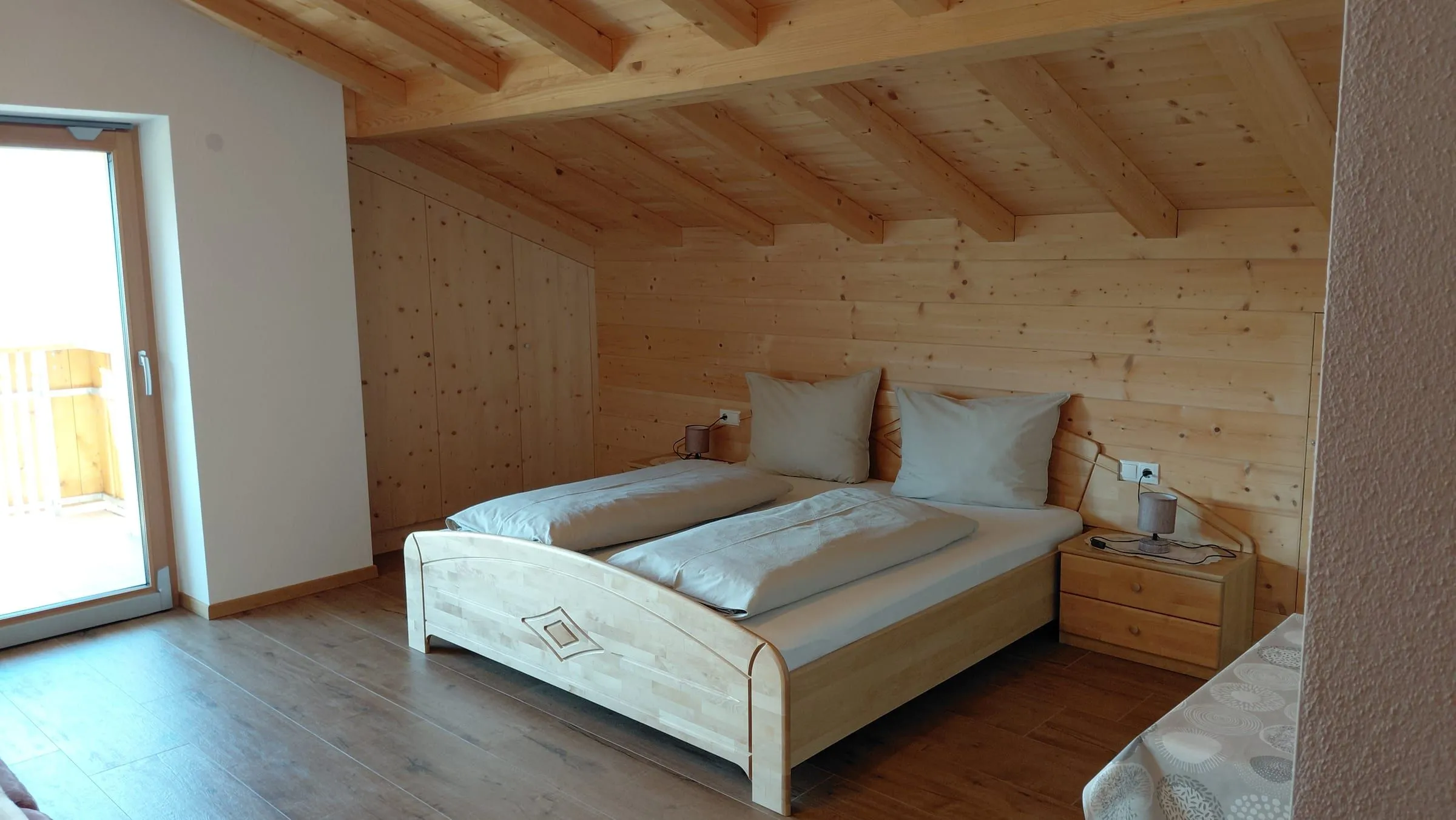 Schlafzimmer der Ferienwohnung mit Holzdecke und Bergblick